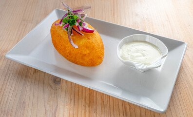  Papa rellena traditional Peruvian cuisine dish with mashed potatoes stuffed with ground beef served with mayonnaise sauce.