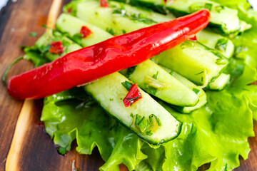 Fresh cucumber salad with red chili served on a wooden platter