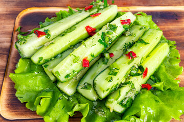 Fresh cucumber salad prepared with herbs and spices on a wooden board