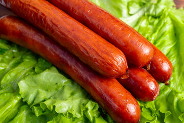 Freshly cooked sausages resting on green lettuce leaves