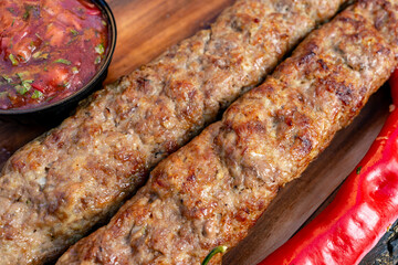 Delicious kebabs served with spicy sauce on a wooden platter