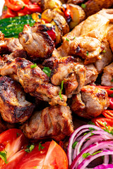 Grilled meat platter featuring assorted cuts and fresh vegetables