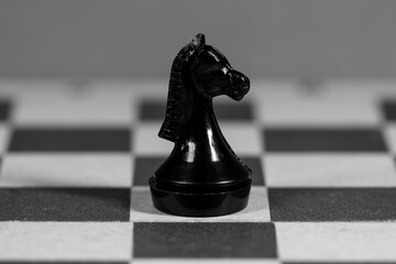A black chess knight figure on a chessboard © Klochkov