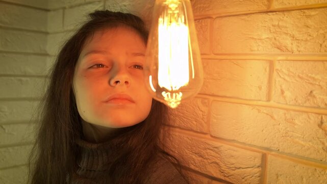 Child look at burning bulb. view of joyful little girl with smile stand by the bulb in light indoor.