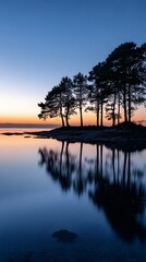 Obraz premium The silhouette of trees on the shore, reflecting in the calm waters at sunset 