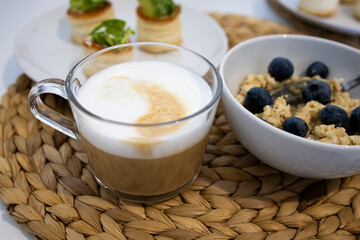 Morning breakfast scene with coffee, oatmeal, and savory pastries on woven place mat