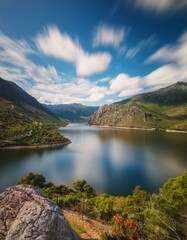 Naklejka premium Un hermoso lago en medio de las montañas, con cielo azul y nubes