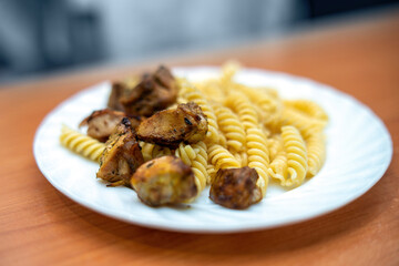 delicious serving of fusilli pasta topped with tender braised white meat seasoned with Provencal herbs, elegantly presented on a white ceramic plate