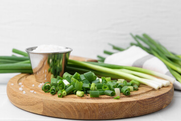 Chopped green onion, stems and salt on white table, closeup