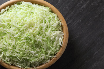 Fresh shredded cabbage on black table, top view