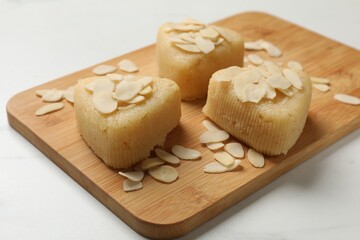 Pieces of delicious semolina halva with almond flakes on white table, closeup