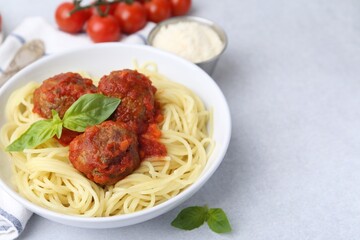 Delicious pasta with meatballs in bowl on light table, closeup. Space for text