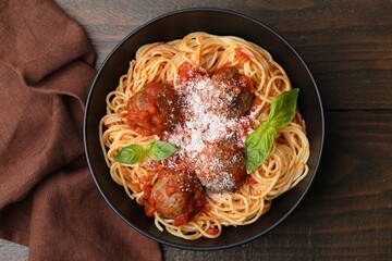 Delicious pasta with meatballs and cheese in bowl on wooden table, top view
