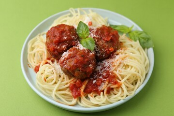 Delicious pasta with meatballs, basil and cheese on green table, closeup
