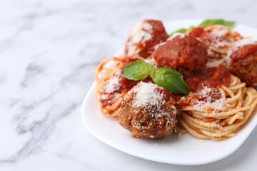 Delicious pasta with meatballs, basil and cheese on white marble table, closeup. Space for text