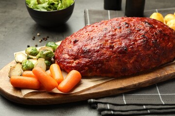 Delicious turkey meatloaf with vegetables on grey table, closeup