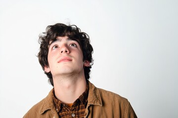 Obraz premium Thoughtful Young Man Looking Upwards Against a Minimalist Background