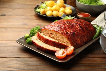 Delicious turkey meatloaf with vegetables on wooden table