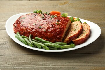 Delicious baked turkey meatloaf with vegetables on wooden table, closeup