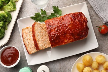 Delicious baked turkey meatloaf with vegetables served on grey table, flat lay