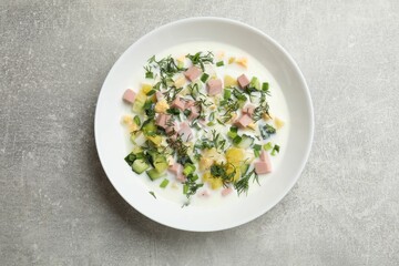 Delicious okroshka soup in bowl on grey textured table, top view