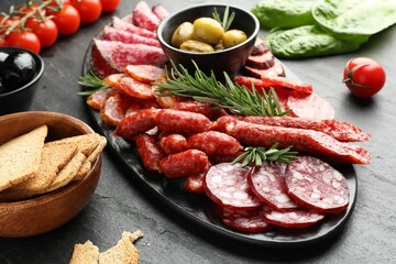 Different smoked sausages and other snacks on black table, closeup