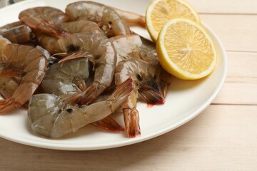 Fresh raw shrimps with lemon on wooden table, closeup