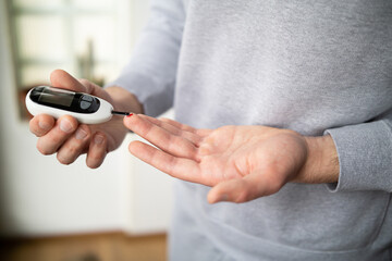 Close-up Of A Man's Hand Checking Blood Sugar Level With Glucometer