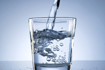 Close-Up of Clear Water Being Poured into a Glass with Bubbles in a Minimalist Setting