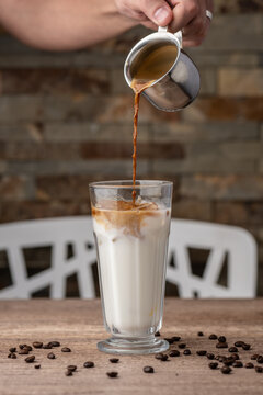 a hand pouring coffee into milk