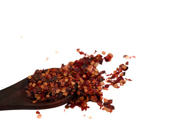Red chili flakes being poured from a wooden spoon