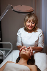 A skilled beautician expertly performs a soothing facial treatment on a client in a tranquil and...
