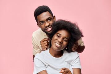 Obraz premium Happy couple enjoying quality time together, with joyful expressions against a pastel pink background, showcasing love and connection in a modern setting