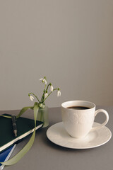 Office and spring concept with cup of coffee and spring flowers.