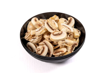 A black dish of sliced brown Cremini mushrooms isolated on white