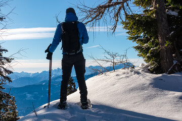 Frozen trees framing hiker man with backpack and snowshoes in snowy Gailtal Alps, Carinthia,...