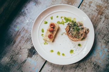 Filet mignon wrapped in bacon, topped with oysters, parsley, accompanied by puff pastry potato.
Served on a white plate.