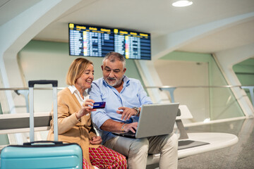 Fototapeta premium Senior couple using laptop and credit card at the airport