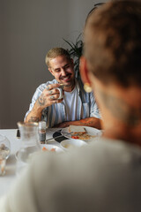 Gay couple smiling and having breakfast at home