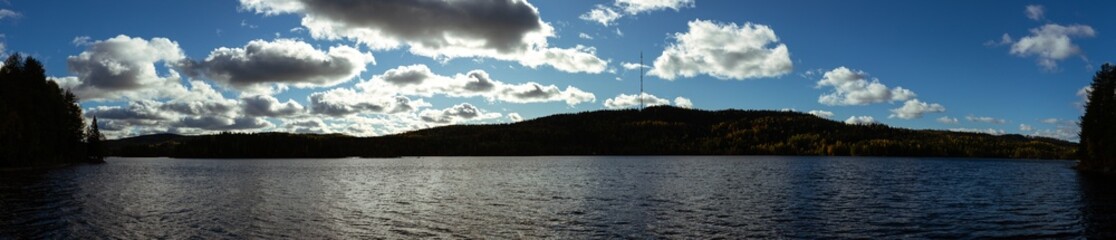 Expansive Nordic Lake Surrounded by Rolling Hills, Autumn Foliage, and a Dramatic Cloudscape in Serene Wilderness