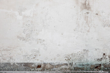 Old brick wall with damaged white stucco layer and paint