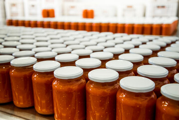Canned tomatoes in a row on a shelf in a food factory