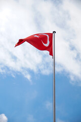 Turkish national flag hanging from a pole in a cloudy sky