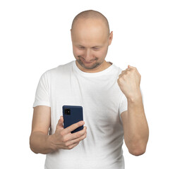 Bald man in white t-shirt celebrating success while looking at smartphone