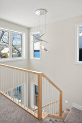A staircase with a wooden railing and a light fixture hanging from the ceiling