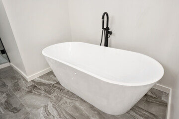 A white bathtub with a black faucet sits in a bathroom