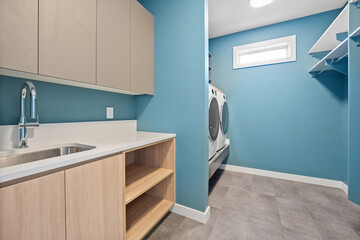 A blue and white bathroom with a sink, washer and dryer