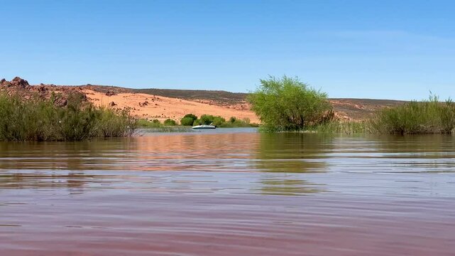 Powerboat rests at anchor on the tranquil waters of Sand Hollow State Park's scenic reservoir, surrounded by Utah's dramatic red rock desert.