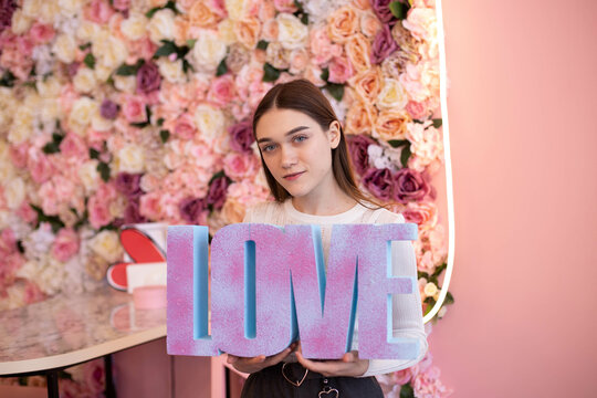 Girl holding the word &ldquo;LOVE&rdquo; on a pink background