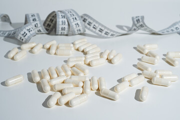 Measuring tape and tablets, vitamins on a light background with space for text. Concept of losing...